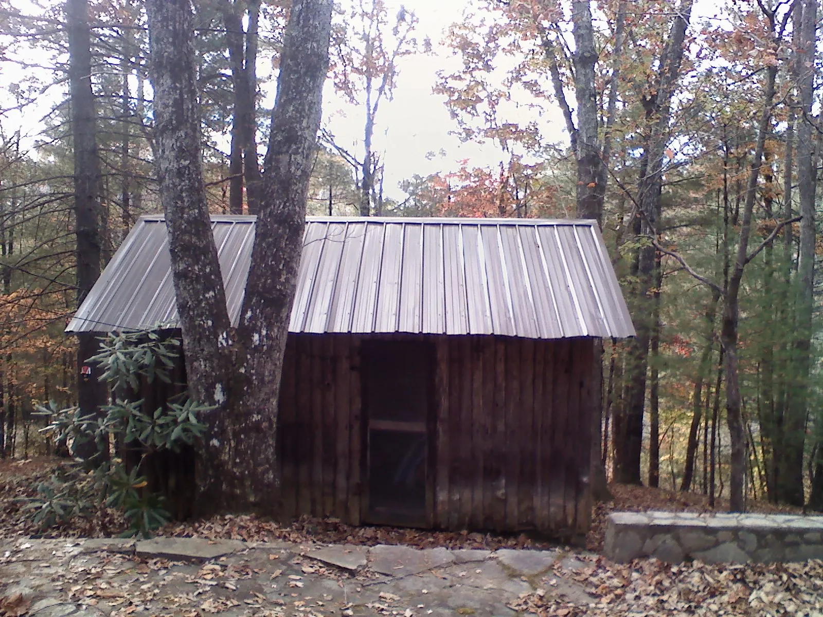 New metal gable roof on a small log shed among the trees in Holland
