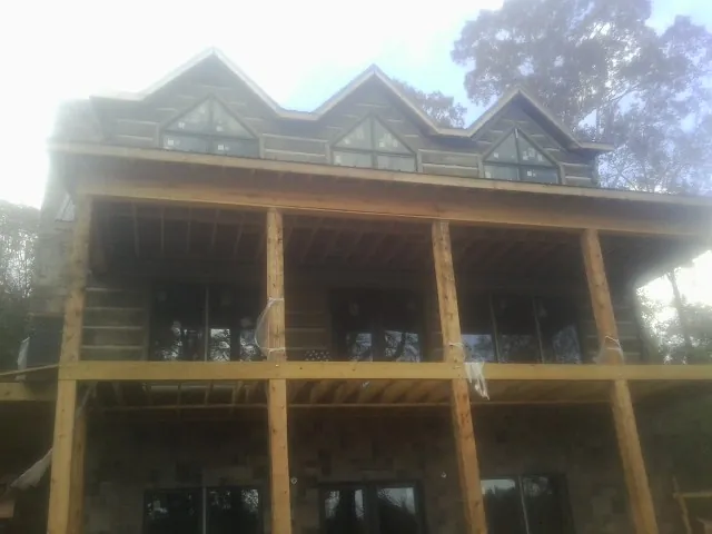 Dormers and porch framing on a large log home under construction — Roof Coating work by our crew in Holland